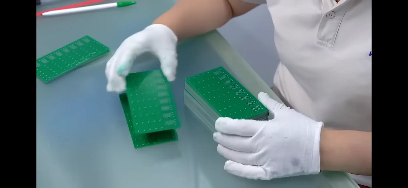 Operator handling finished PCB panels using protective gloves